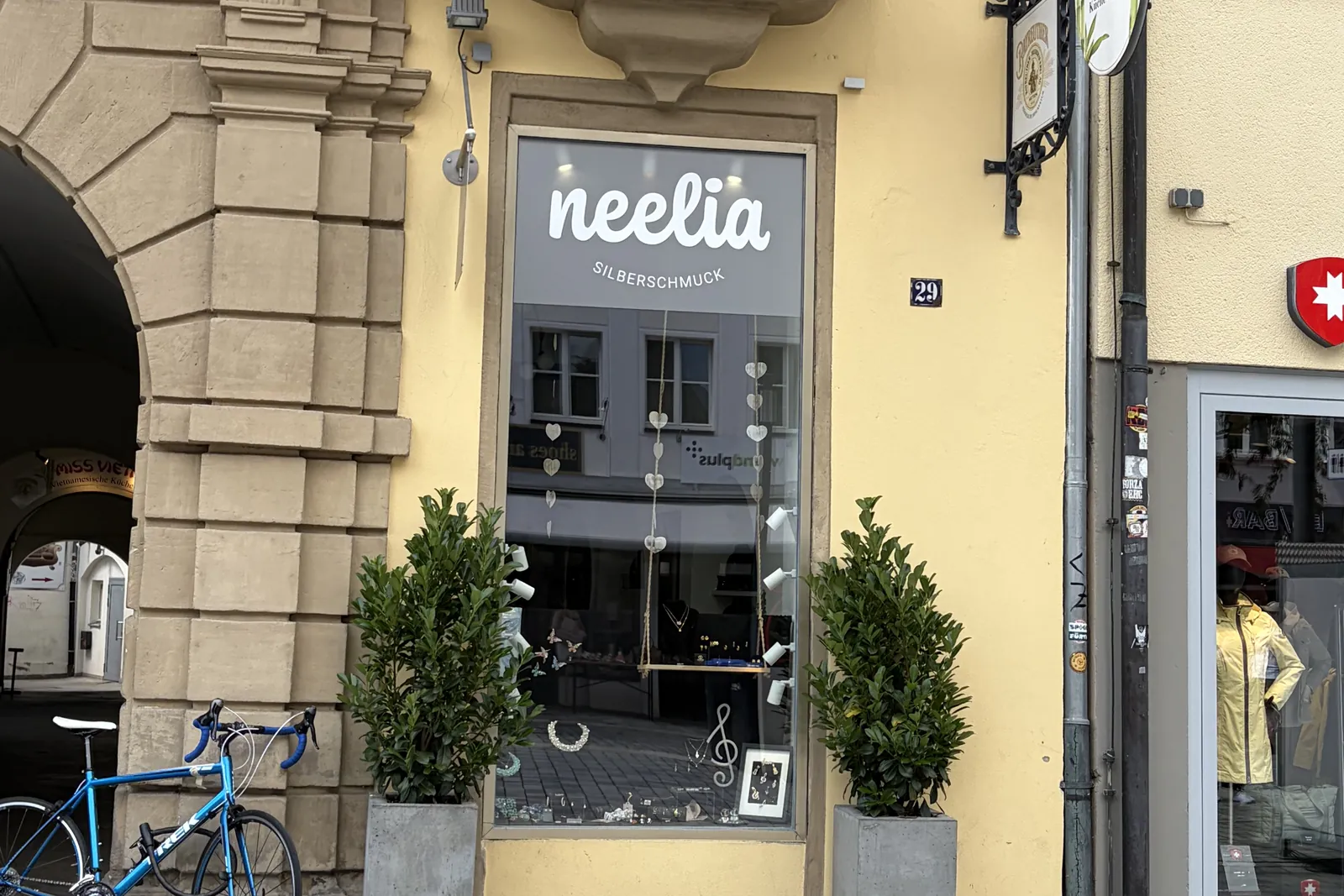 Schaufenster von neelia in der Maximilianstraße 29 in Bayreuth mit Schriftzug neelia Silberschmuck und zwei Buchsbäumen im Kübel